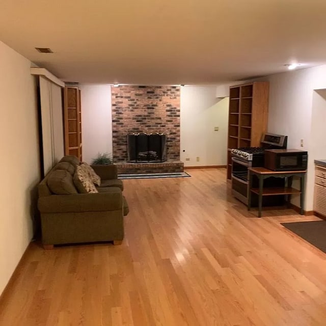 living room featuring light hardwood / wood-style floors and a brick fireplace