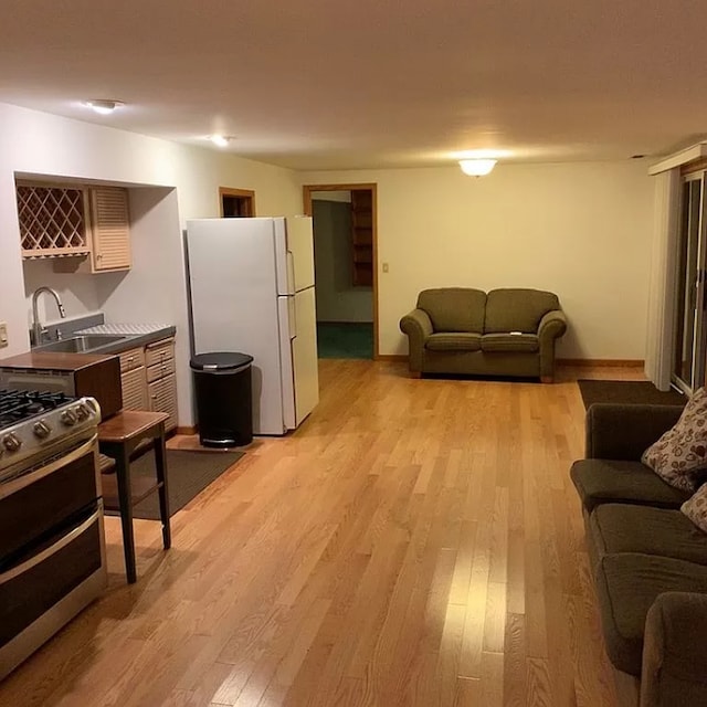 kitchen with white fridge, range, sink, and light hardwood / wood-style flooring