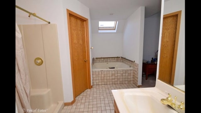 bathroom featuring vanity, a skylight, tile patterned floors, and tiled tub