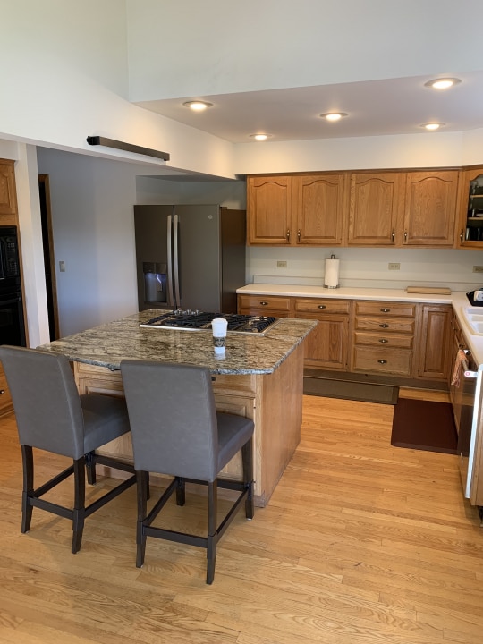 kitchen featuring a kitchen breakfast bar, light hardwood / wood-style floors, light stone countertops, and stainless steel appliances