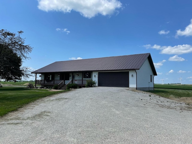 view of front of home with metal roof, a porch, a garage, a front yard, and gravel driveway