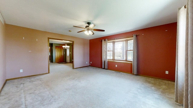 empty room featuring light carpet, baseboards, and ceiling fan with notable chandelier