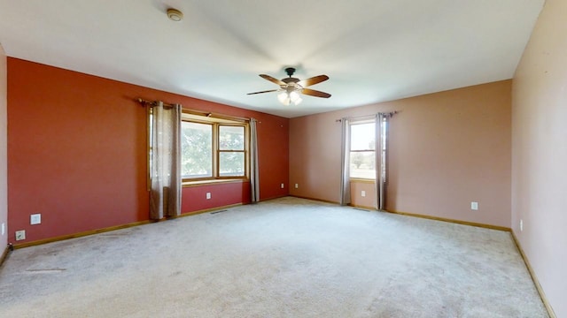 spare room featuring light carpet, a ceiling fan, and baseboards