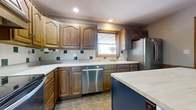 kitchen with stainless steel appliances, brown cabinetry, light countertops, and under cabinet range hood