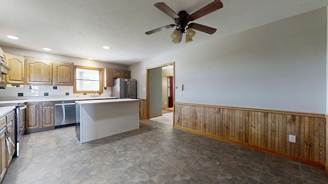 kitchen featuring wooden walls, appliances with stainless steel finishes, light countertops, and wainscoting