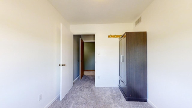 unfurnished room featuring light colored carpet, visible vents, and baseboards