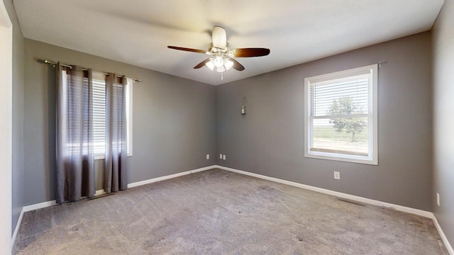 spare room featuring light carpet, ceiling fan, and baseboards