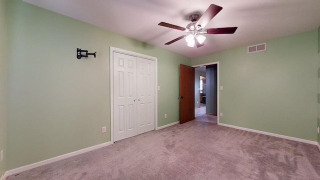 unfurnished bedroom with baseboards, visible vents, light colored carpet, ceiling fan, and a closet