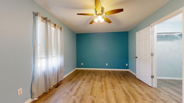 unfurnished bedroom featuring light wood-style floors, baseboards, and a ceiling fan