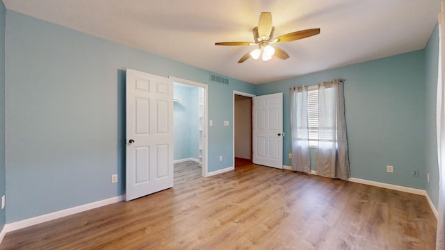 unfurnished bedroom with baseboards, visible vents, a ceiling fan, a spacious closet, and light wood-type flooring