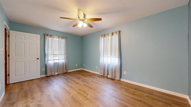 unfurnished bedroom featuring light wood-style floors, baseboards, and a ceiling fan