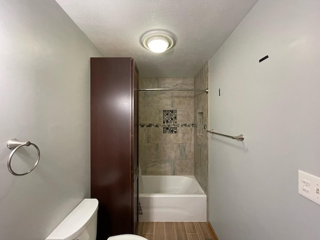 bathroom featuring toilet, a textured ceiling,  shower combination, and wood finished floors