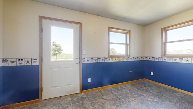 doorway to outside featuring stone finish floor and baseboards