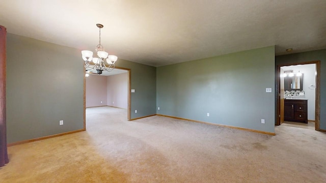 empty room with baseboards, a notable chandelier, and light colored carpet