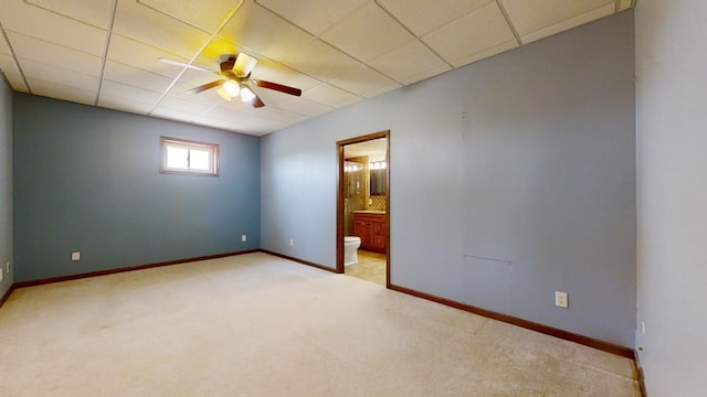 unfurnished bedroom featuring light carpet, a drop ceiling, and baseboards