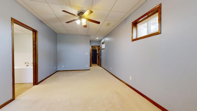 unfurnished room featuring baseboards, a drop ceiling, a ceiling fan, and light colored carpet