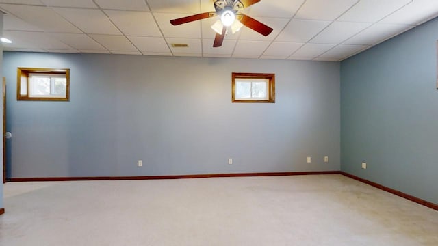 carpeted spare room with plenty of natural light, baseboards, and a drop ceiling