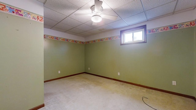 spare room featuring a ceiling fan, baseboards, a drop ceiling, and light colored carpet