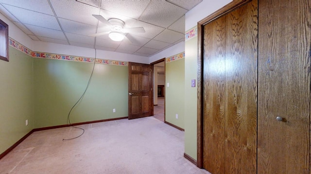 unfurnished bedroom with baseboards, a closet, a paneled ceiling, and light colored carpet