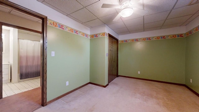 empty room with a paneled ceiling, ceiling fan, and baseboards