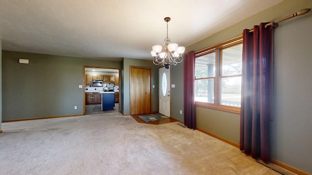 interior space featuring light carpet, baseboards, and a notable chandelier