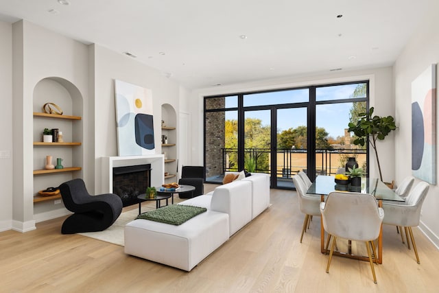 living room with built in shelves and light hardwood / wood-style flooring