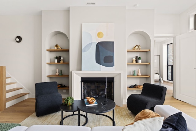 living room with built in shelves and light hardwood / wood-style floors