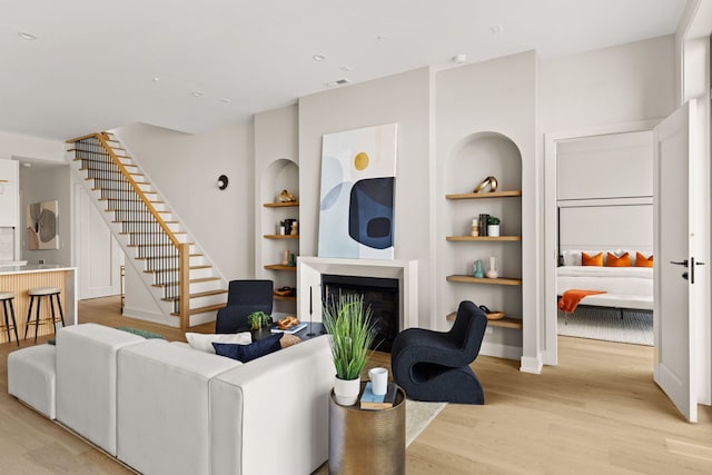 living room featuring built in shelves and light hardwood / wood-style floors