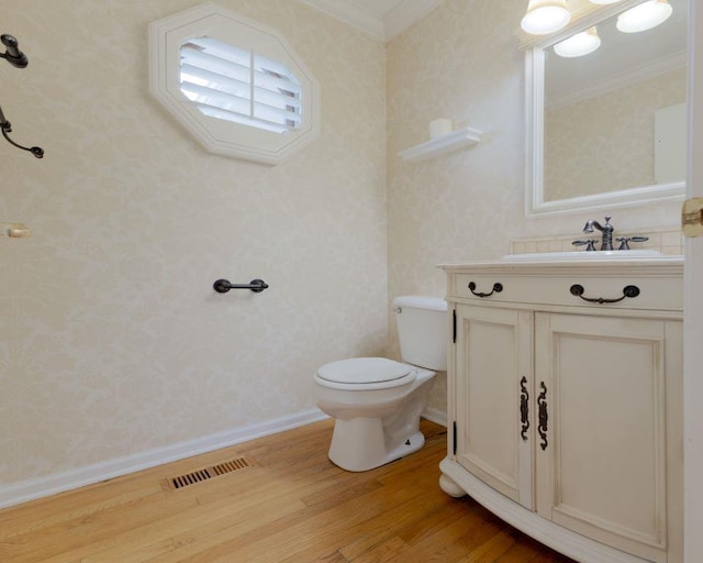 bathroom featuring hardwood / wood-style floors, ornamental molding, vanity, and toilet