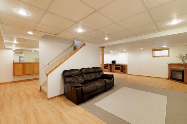 living room featuring a drop ceiling and light hardwood / wood-style flooring