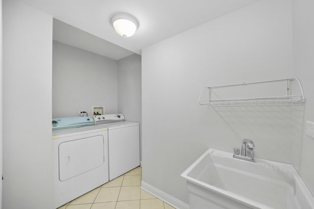 laundry room featuring washing machine and clothes dryer, light tile patterned floors, and sink