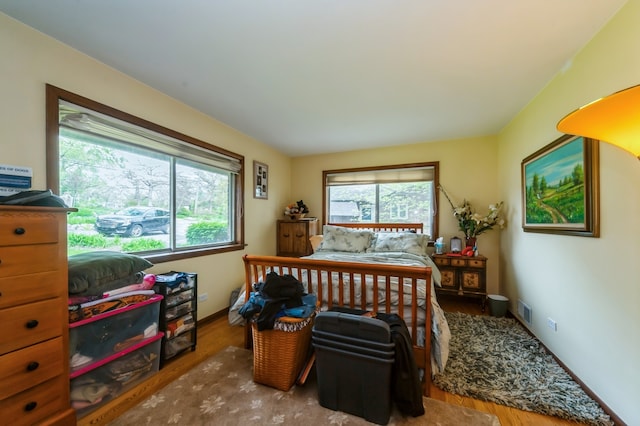 bedroom with multiple windows and hardwood / wood-style flooring