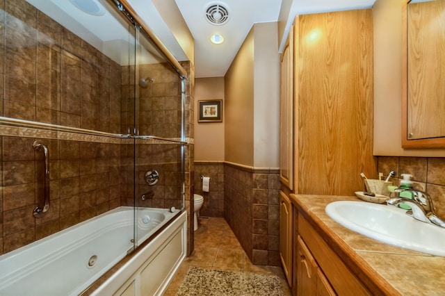 full bathroom featuring tile walls, bath / shower combo with glass door, large vanity, toilet, and tile flooring