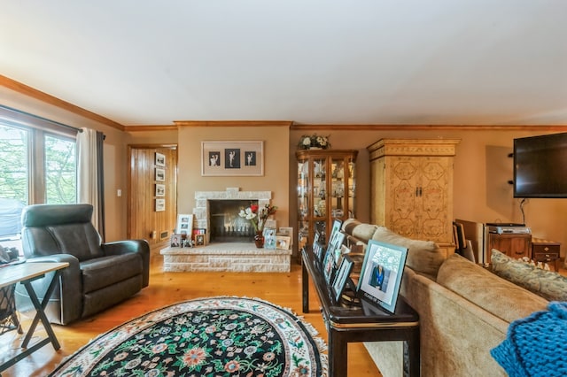 living room with a stone fireplace, wood-type flooring, and crown molding