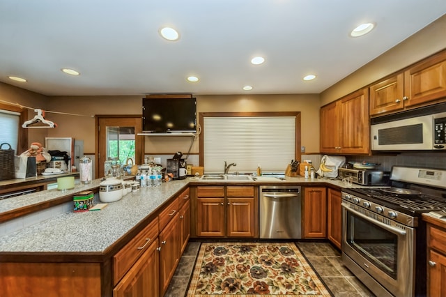 kitchen with sink, dark tile floors, stainless steel appliances, and kitchen peninsula