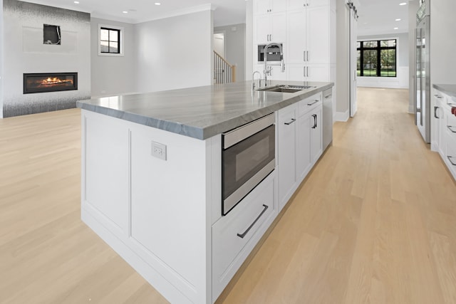 kitchen with light hardwood / wood-style floors, sink, an island with sink, and stainless steel appliances