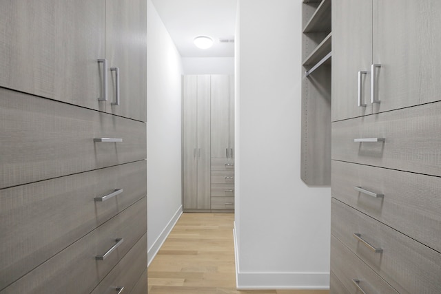 walk in closet with light hardwood / wood-style flooring