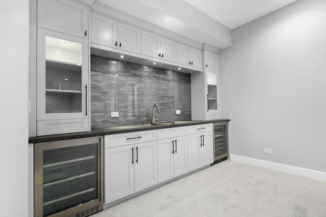 kitchen with wine cooler, decorative backsplash, light carpet, and white cabinets