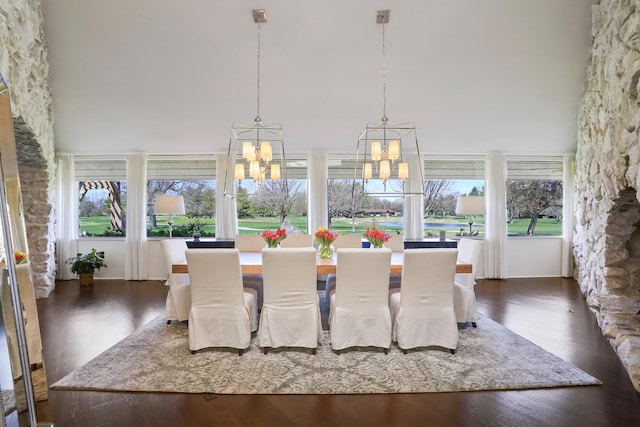 dining space featuring a notable chandelier, dark wood-type flooring, and a high ceiling