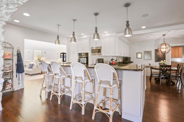 kitchen with hanging light fixtures, dark hardwood / wood-style flooring, stainless steel microwave, white cabinets, and oven