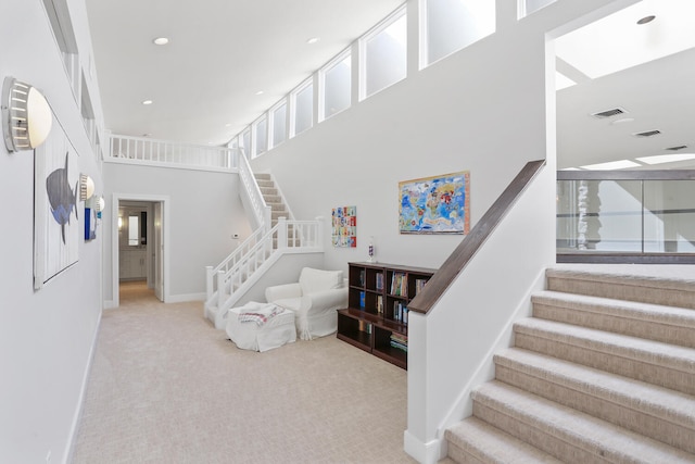 stairway featuring light carpet and a high ceiling