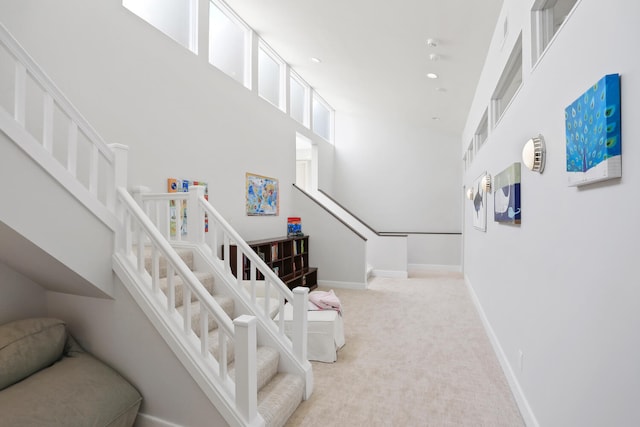 stairs featuring a towering ceiling and carpet floors