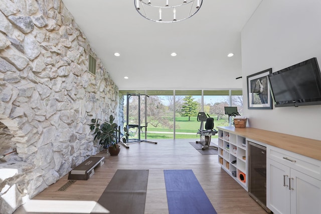 exercise area with plenty of natural light, dark hardwood / wood-style flooring, a notable chandelier, and beverage cooler