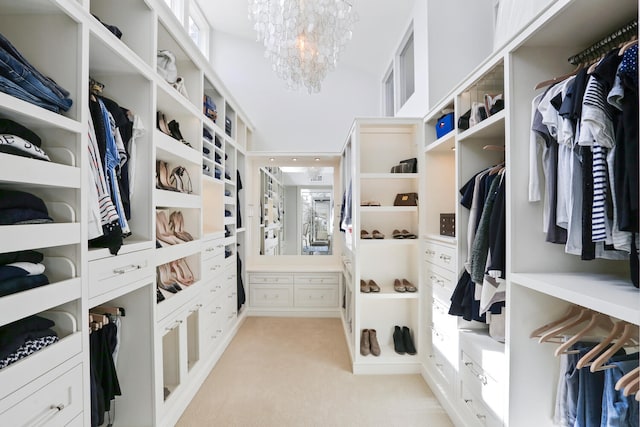 walk in closet featuring light colored carpet and a notable chandelier