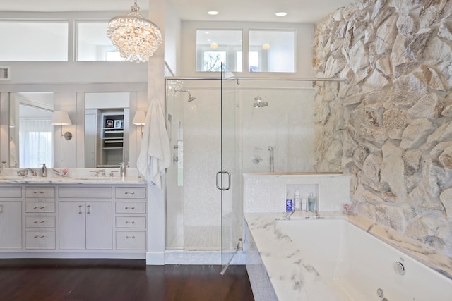 bathroom featuring vanity with extensive cabinet space, hardwood / wood-style flooring, separate shower and tub, and an inviting chandelier