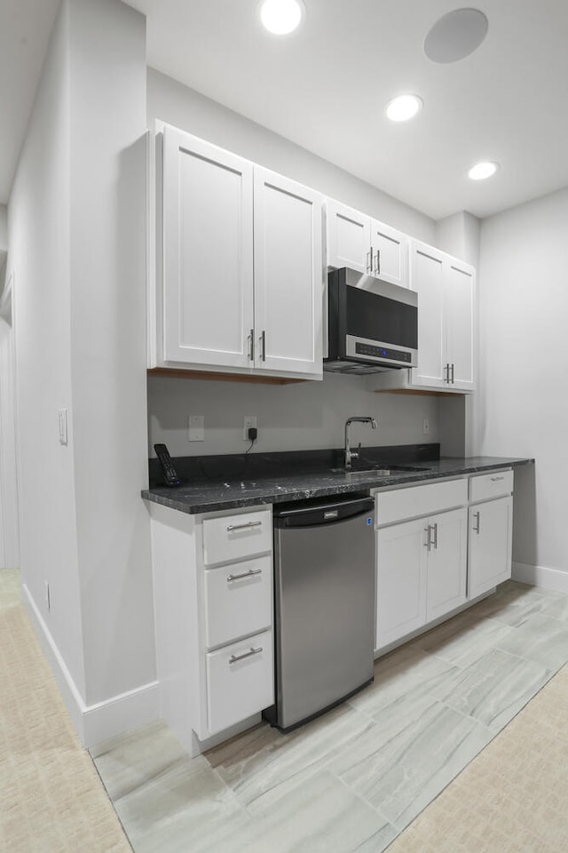 kitchen featuring dark stone counters, stainless steel appliances, white cabinets, sink, and light tile floors