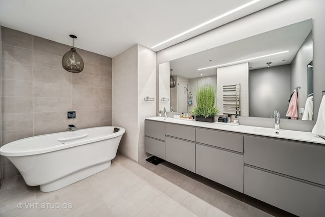 bathroom featuring a bath, tile patterned floors, double sink vanity, and tile walls