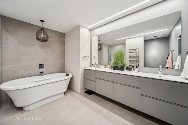 bathroom with tile walls, radiator heating unit, vanity, tile patterned floors, and independent shower and bath