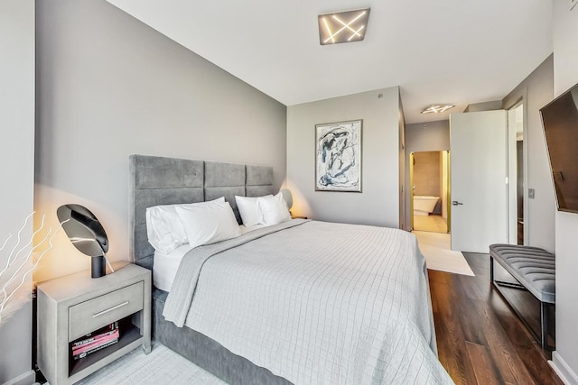 bedroom featuring ensuite bath and hardwood / wood-style floors