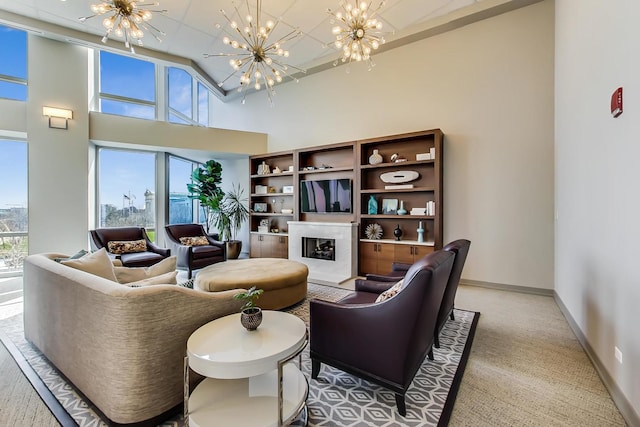 living room with carpet, a fireplace, a towering ceiling, and a chandelier